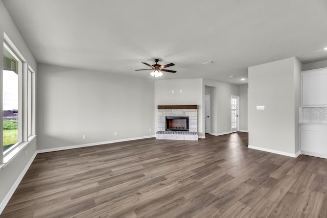 unfurnished living room with ceiling fan, a fireplace, and wood-type flooring