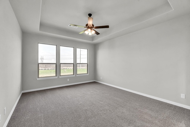 unfurnished room with carpet flooring, a raised ceiling, and ceiling fan