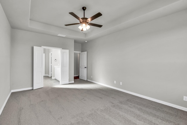 unfurnished bedroom with ceiling fan, light carpet, and a tray ceiling