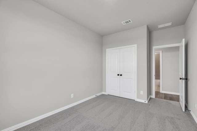 unfurnished bedroom featuring light colored carpet and a closet