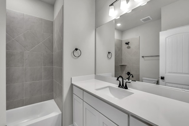 full bathroom featuring vanity, tiled shower / bath, and toilet