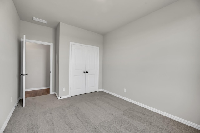 unfurnished bedroom featuring light colored carpet and a closet