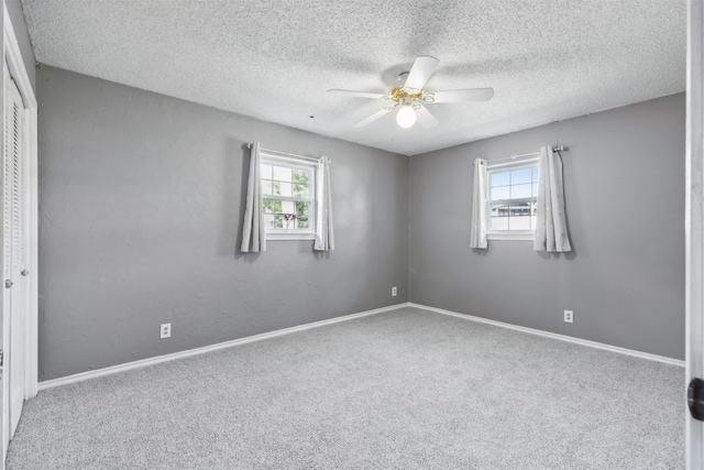 empty room featuring ceiling fan, a textured ceiling, plenty of natural light, and carpet flooring