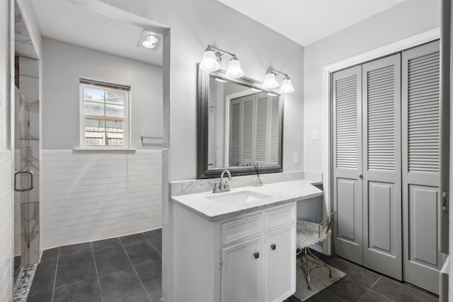 bathroom featuring tile walls, vanity, a closet, tile patterned floors, and a stall shower