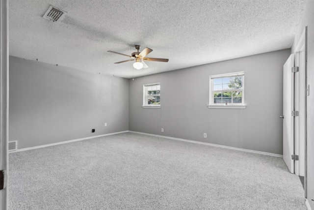 carpeted spare room with baseboards, visible vents, a ceiling fan, and a textured ceiling