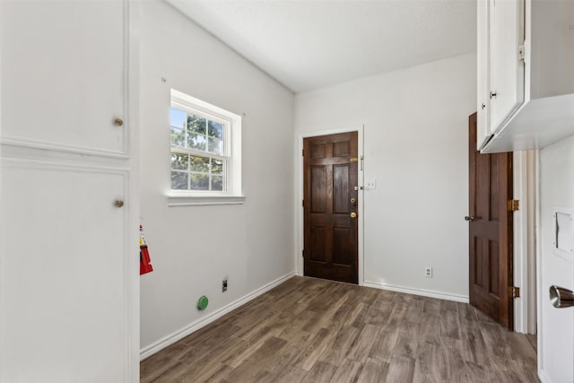 laundry room featuring electric dryer hookup, a textured ceiling, wood-type flooring, and cabinets