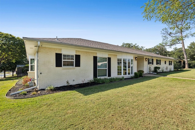 ranch-style home featuring a front lawn, a shingled roof, and brick siding