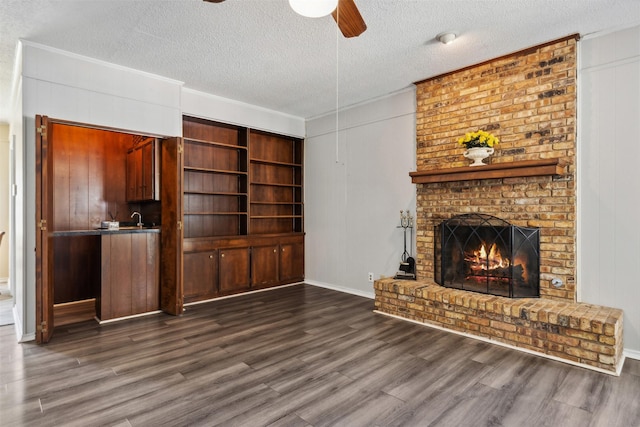 unfurnished living room with a fireplace, a textured ceiling, ceiling fan, and dark wood-type flooring