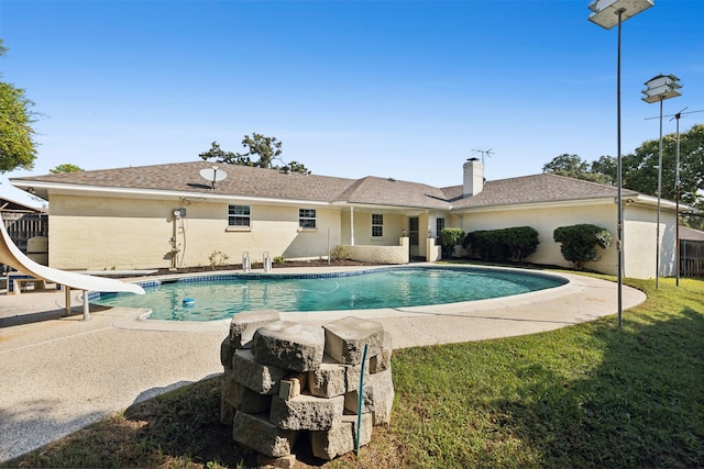 view of swimming pool with a yard, a water slide, and a patio area