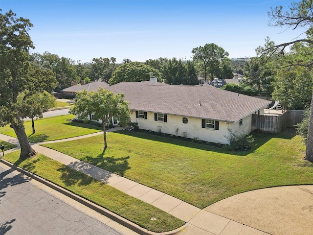 ranch-style house with fence, a chimney, a front yard, and stucco siding