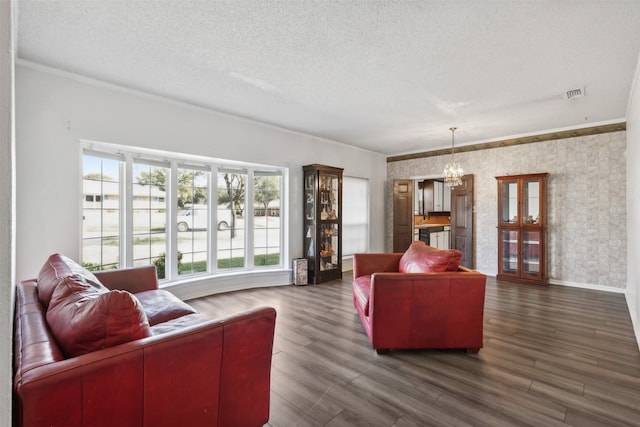 living room featuring ornamental molding, a chandelier, dark hardwood / wood-style floors, and a textured ceiling