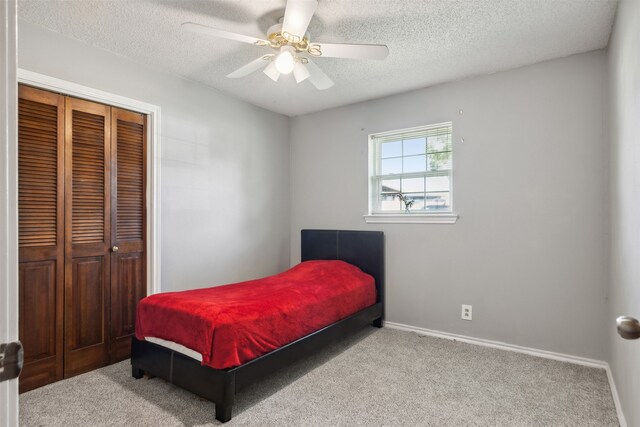 bedroom featuring ceiling fan, a textured ceiling, a closet, and light carpet