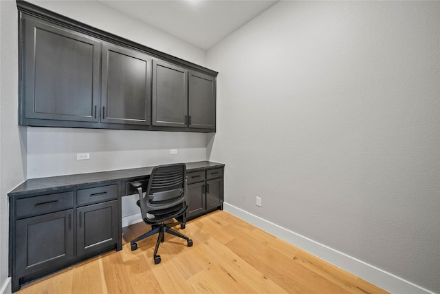 office with built in desk and light hardwood / wood-style flooring