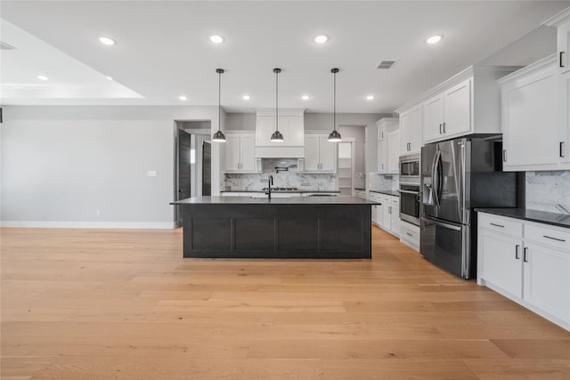 kitchen with stainless steel appliances, white cabinetry, hanging light fixtures, and a kitchen island with sink