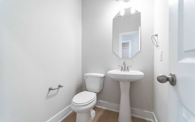 bathroom featuring wood-type flooring, toilet, and sink