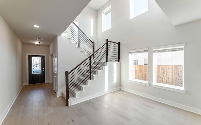 entrance foyer featuring a high ceiling, light wood-type flooring, and a wealth of natural light