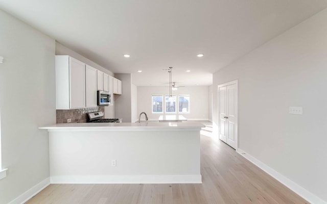 kitchen with sink, tasteful backsplash, kitchen peninsula, white range with electric cooktop, and decorative light fixtures