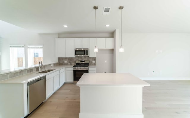 kitchen featuring sink, white cabinets, pendant lighting, and appliances with stainless steel finishes