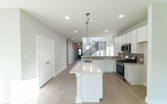 kitchen featuring white cabinetry, sink, stainless steel appliances, backsplash, and pendant lighting