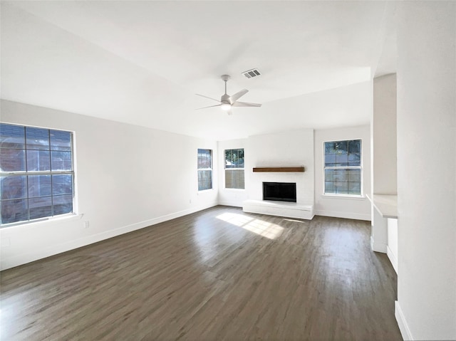 unfurnished living room with a brick fireplace, ceiling fan, and dark wood-type flooring