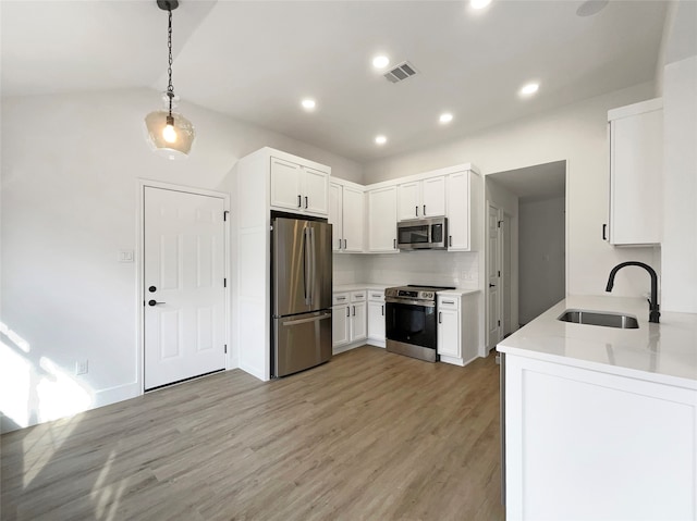 kitchen with white cabinetry, appliances with stainless steel finishes, decorative light fixtures, and sink