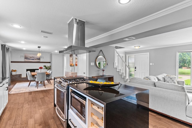 kitchen featuring white cabinets, island exhaust hood, a textured ceiling, stainless steel gas range, and light hardwood / wood-style floors