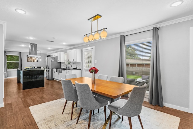 dining area with sink, crown molding, and dark hardwood / wood-style flooring