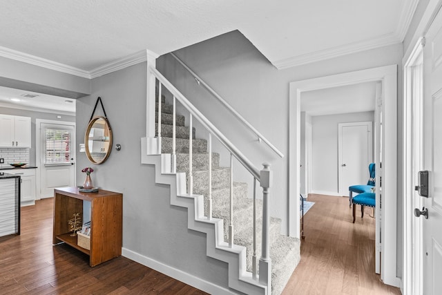 stairs with wood-type flooring and crown molding