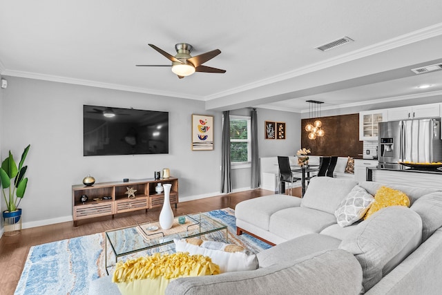 living room featuring ceiling fan with notable chandelier, ornamental molding, and dark wood-type flooring