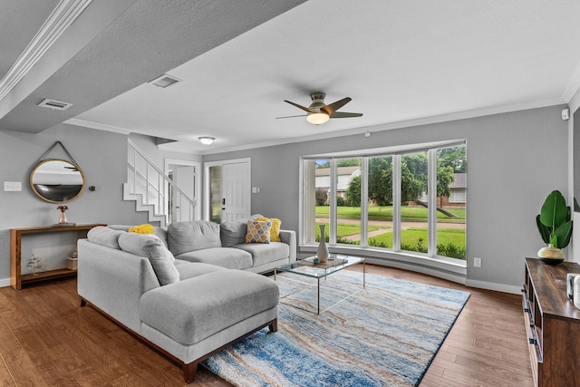 living room featuring a textured ceiling, ceiling fan, dark wood-type flooring, and crown molding