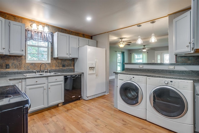 kitchen with hanging light fixtures, black appliances, washing machine and dryer, light wood-type flooring, and decorative backsplash