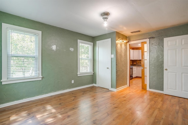 unfurnished bedroom featuring light wood-type flooring and connected bathroom