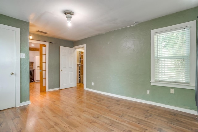 unfurnished bedroom featuring white refrigerator with ice dispenser and light wood-type flooring