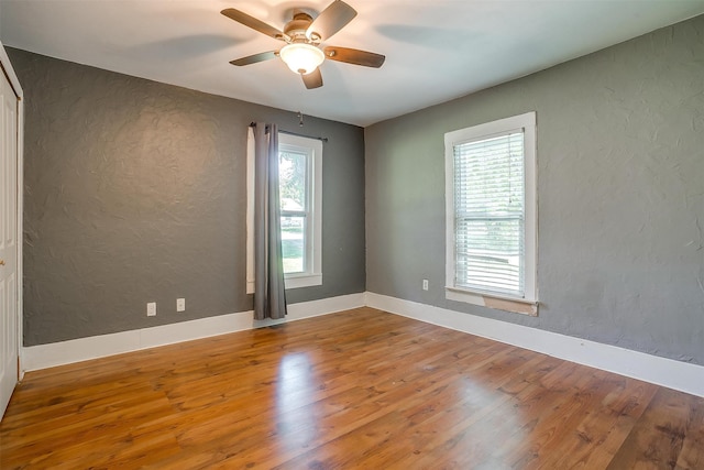 unfurnished room featuring a wealth of natural light, ceiling fan, and hardwood / wood-style flooring