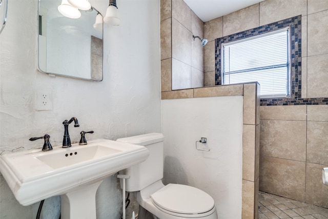 bathroom featuring toilet, sink, and tiled shower