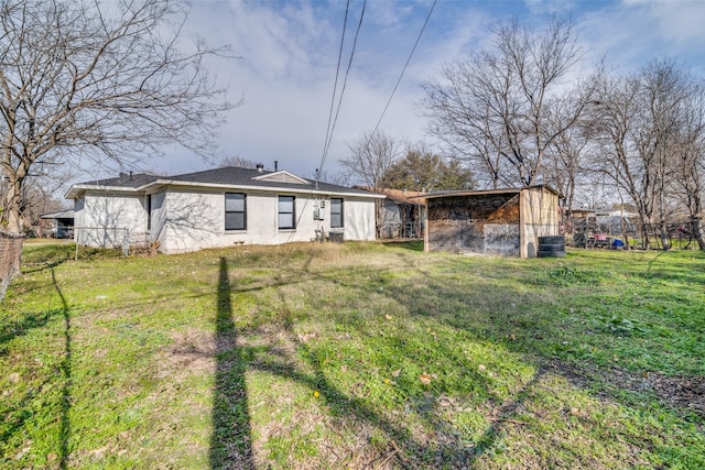 back of house with central AC unit, an outdoor structure, and a lawn