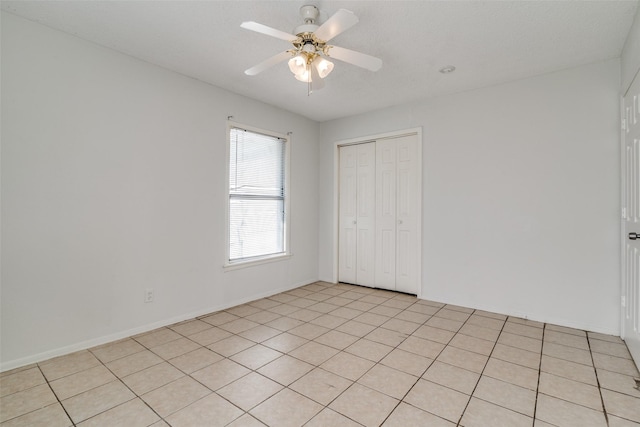 empty room with ceiling fan and light tile patterned floors