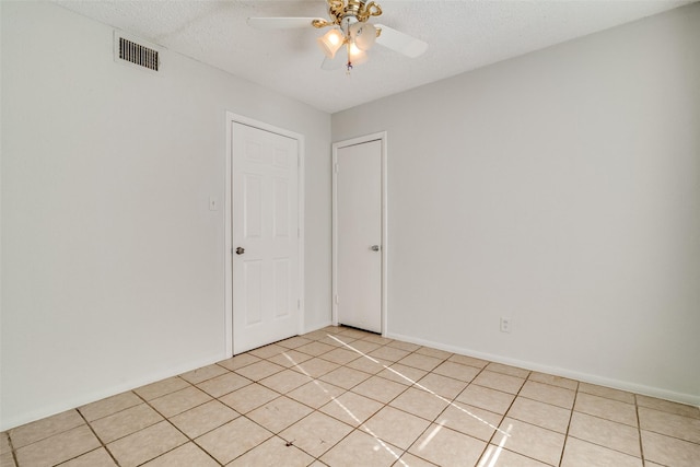 unfurnished room featuring a textured ceiling, ceiling fan, and light tile patterned flooring