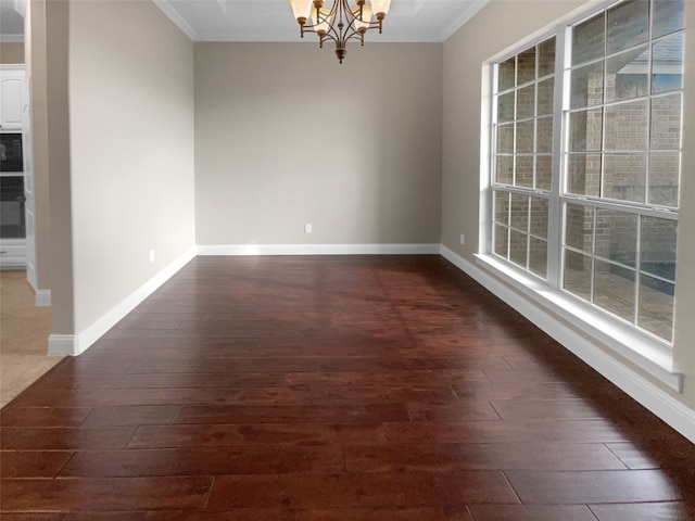 empty room featuring dark hardwood / wood-style floors, ornamental molding, and a chandelier