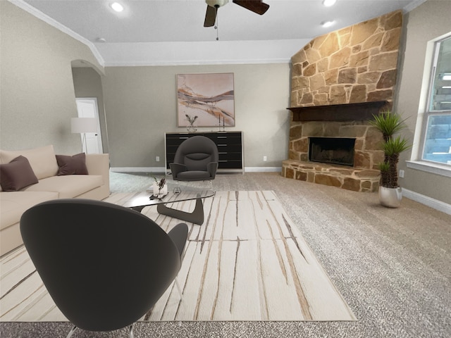 carpeted living room with ceiling fan, a fireplace, and crown molding