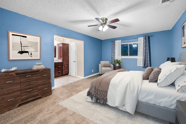 carpeted bedroom featuring ensuite bathroom, ceiling fan, and a textured ceiling