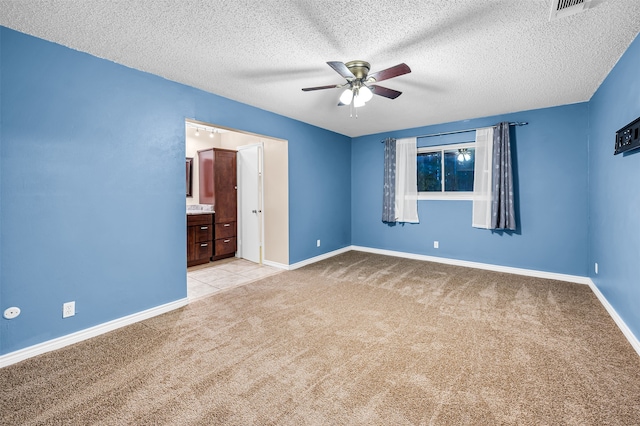 unfurnished bedroom featuring light carpet, a textured ceiling, and ceiling fan