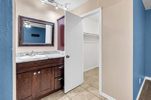 bathroom with tile patterned flooring, vanity, ceiling fan, and a textured ceiling