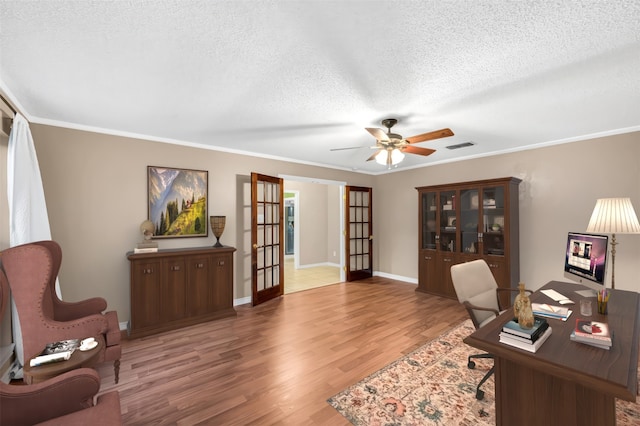 home office with ceiling fan, french doors, wood-type flooring, a textured ceiling, and ornamental molding