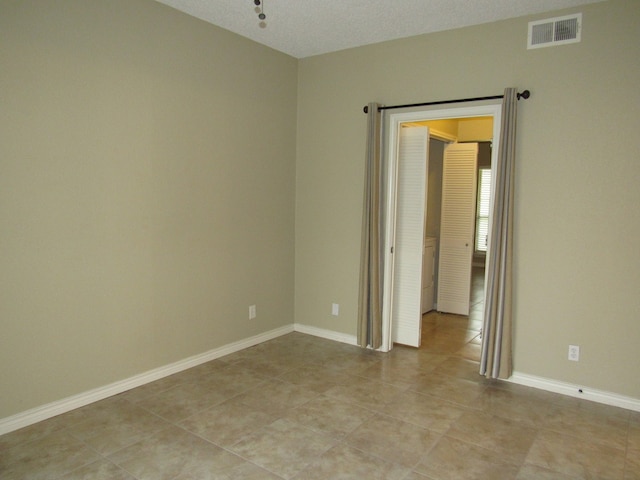 tiled spare room featuring a textured ceiling