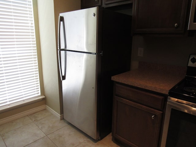 kitchen with dark brown cabinets, light tile patterned floors, and stainless steel appliances