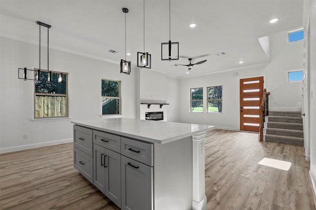 kitchen with light hardwood / wood-style floors, a kitchen island, gray cabinets, and decorative light fixtures