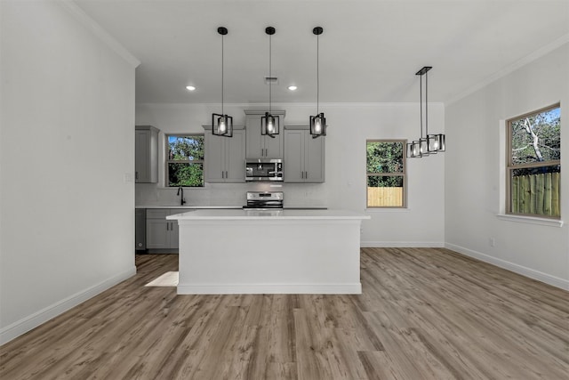 kitchen featuring gray cabinets, stainless steel appliances, decorative light fixtures, and a healthy amount of sunlight