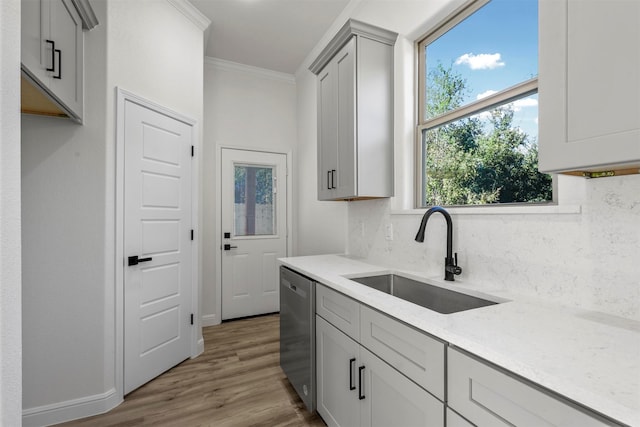 kitchen with light stone counters, sink, dishwasher, gray cabinets, and light wood-type flooring