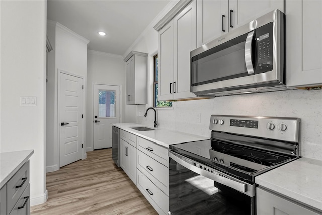 kitchen featuring light wood-type flooring, tasteful backsplash, sink, appliances with stainless steel finishes, and crown molding